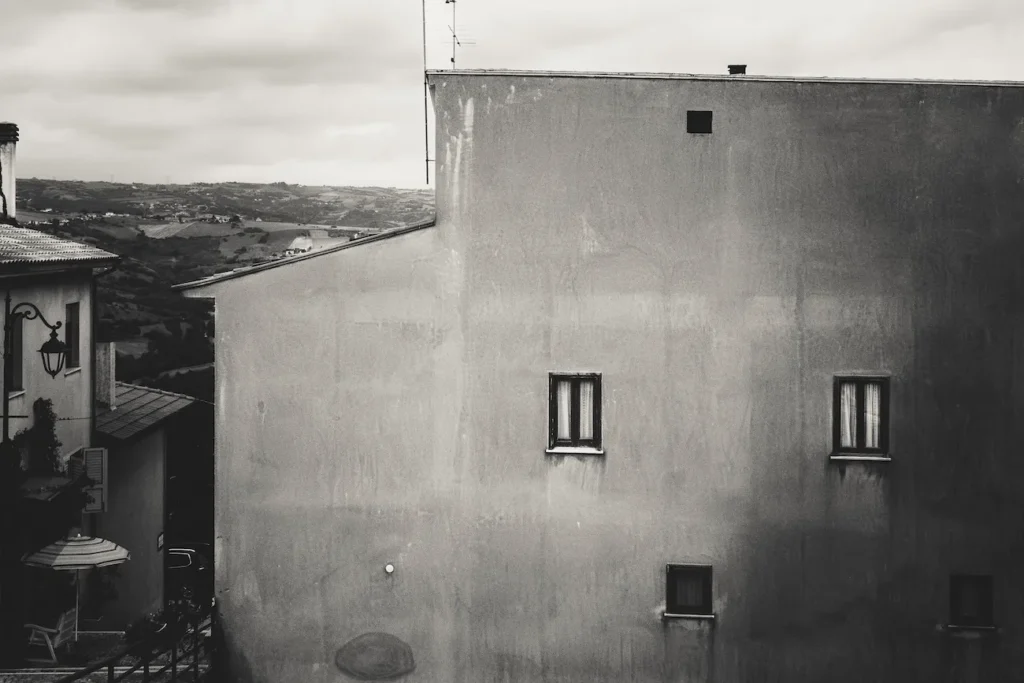 Facciata spoglia di un edificio in Irpinia con vista sulle colline, simbolo dell’architettura del silenzio.