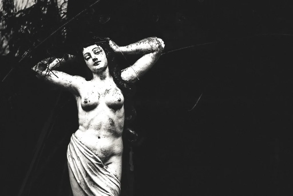 Nel buio emerge una statua femminile, isolata come un frammento fuori dal tempo.