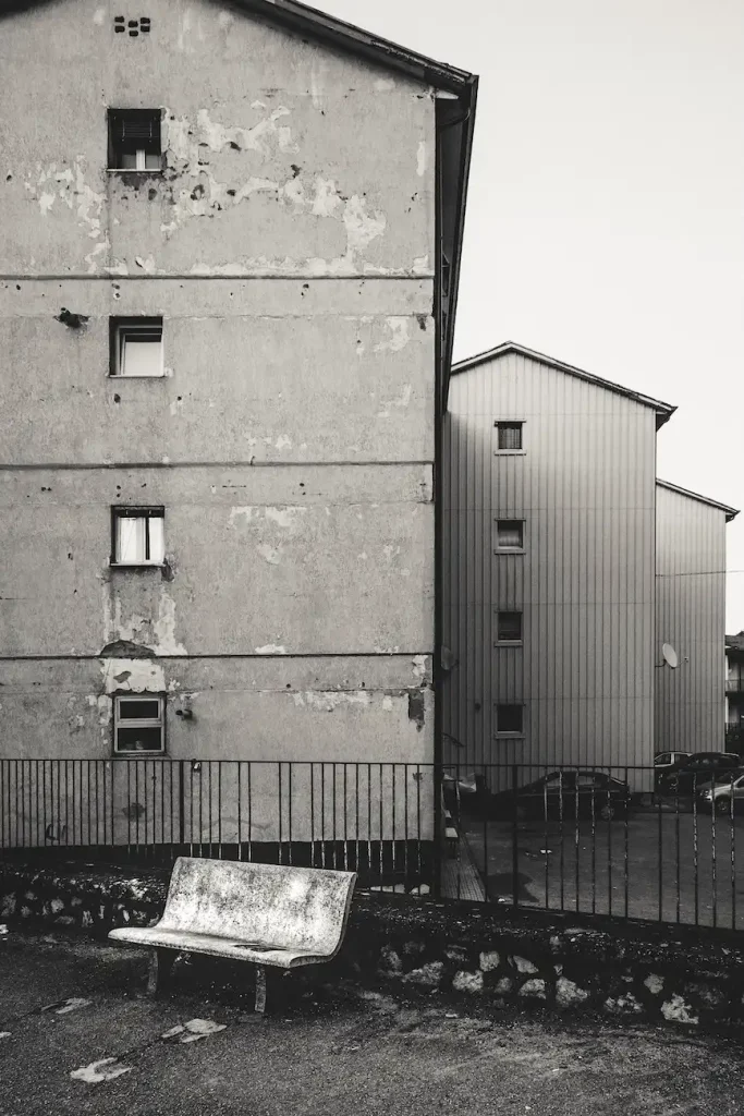 Panchina vuota davanti a edifici segnati dal tempo, in un margine urbano di Avellino.
